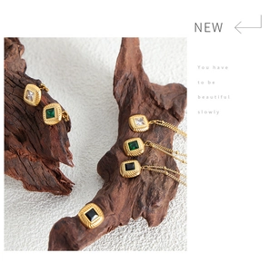 Detailed macro of gold square pendant jewelry set on dark natural wood props