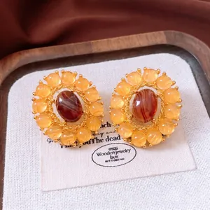 Vintage style gold-rimmed earrings featuring oval agate gemstones on a textured canvas base