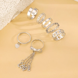 Detail of 7-piece silver ring set featuring heart charms, bow details and LOVE pendants