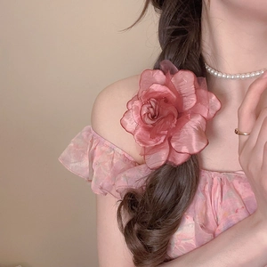 Side view of a large pink fabric rose hair clip worn by a model in a romantic style