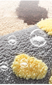 Close-up of thick tufted gray and yellow bathroom mat showing soft fiber texture