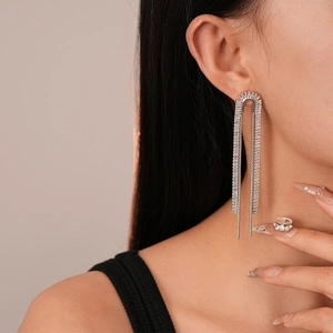 Detail of silver-colored tassel earrings with cubic zirconia on a model for luxury feel