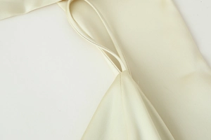 Close-up of champagne satin fabric showing silky texture and delicate sewing detail