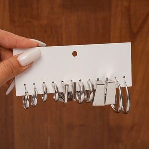 Close-up of 6 pairs of silver geometric C-shape and round hoop earrings on a display card
