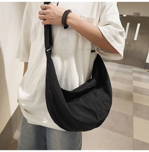 Modèle portant un sac bandoulière en nylon noir en forme de croissant au style urbain