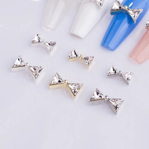 Close-up of sparkling bow tie nail charms with K9 triangle crystals on color swatches