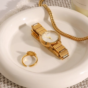 Golden quartz watch set with matching ring and necklace on an elegant white ceramic tray