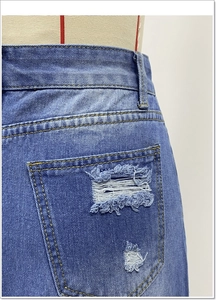 Dettaglio di gonna in denim con tasche strappate e cuciture a contrasto gialle stile vintage