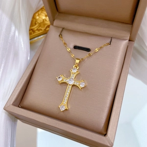 Elegant gold cross necklace with sparkling cubic zirconia on a white silk background
