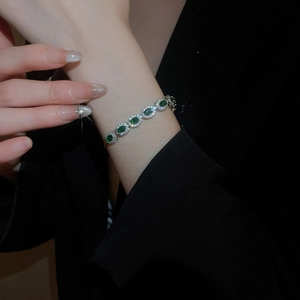 Détail d'un bracelet en zircon vert ovale avec monture argentée porté par un mannequin