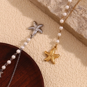 Detailed view of silver and gold starfish pendant necklaces with pearls on beige texture