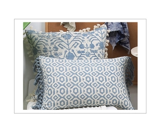 Nahaufnahme von blau-weißen getufteten Kissenbezügen mit Fransen und geometrischem Muster.