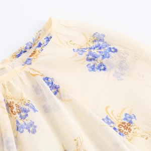 Dettaglio della stampa floreale su chiffon giallo semitrasparente con pieghe sul collo