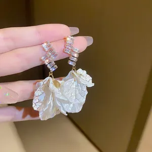 Détail de boucles d'oreilles pétales avec zircons taille escalier et breloques à fleurs