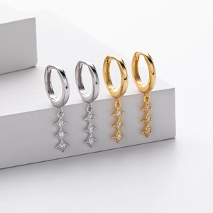 Vue détaillée de créoles en argent et or avec des pendentifs en forme d'étoile scintillants