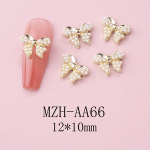 Macro view of gold alloy bow nail charms with white faux pearls and hollow design