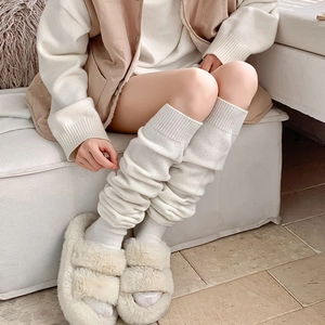 Detail of white cable knit leg warmers with thick ribbed texture for winter warmth
