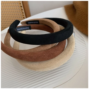 Three thin suede padded headbands in black, brown and beige colors on glass plate