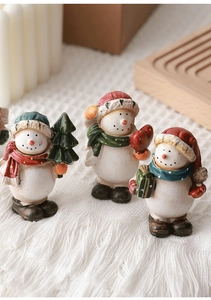 Close-up of three hand-painted resin Christmas snowman figurines with scarves and gifts