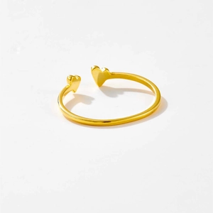 Detailed view of gold open ring with dual heart design and polished metallic finish