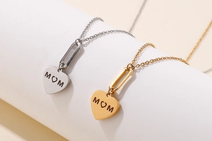 Close-up of heart-shaped MOM pendants in gold and silver finish on a display stand