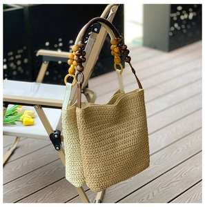 Detail of woven straw shoulder bags with stylish wooden bead and leather straps