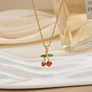 Minimalist cherry pendant necklace with red crystals and gold chain on elegant display