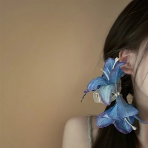 Detailopname van een blauwe lelie haarklem met gradiënt bloemblaadjes op model