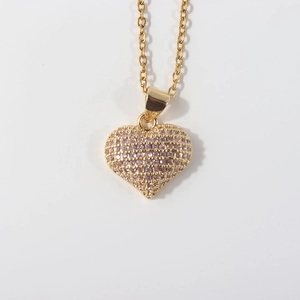 Close-up of heart-shaped gold-plated necklace with pink cubic zirconia stones