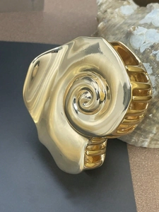 Detail of a golden seashell hair claw clip with vintage geometric metal design