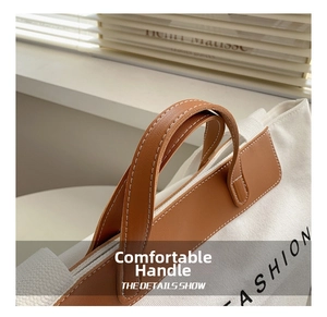 Detail of canvas tote bag with brown leather handles and decorative white stitching