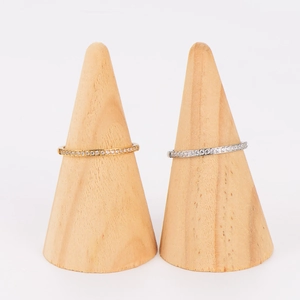 Anillos minimalistas en oro y plata con pavé de circonitas sobre soportes de madera
