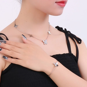 Detailed view of silver butterfly necklace and bracelet set worn by a model on white background