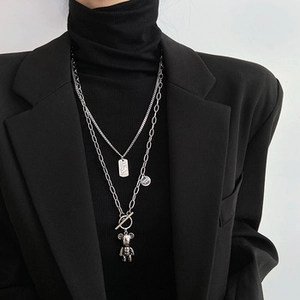 Detail view of layered silver-toned necklaces with 3D bear pendant and OT buckle on a model