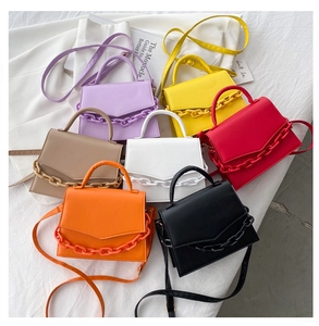 Collection of colorful mini flap bags with chunky chain detail on a white fabric backdrop