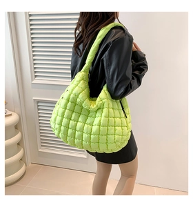 Detail view of a bright green quilted puffer cloud bag worn over the shoulder by a model