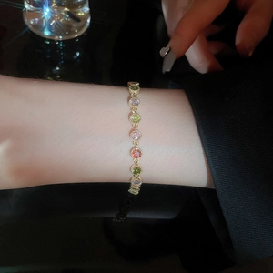 Detail of gold plated bracelet featuring round colorful cubic zirconia on a wrist