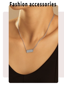 Close-up of silver rectangle engraved pendant necklace worn on neck by a model