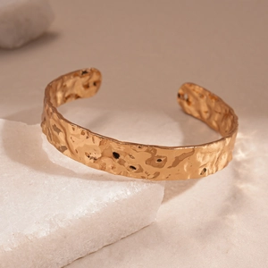 Detailed view of golden hammered texture on a wide geometric open cuff bracelet