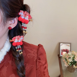 Detail of red embroidered horse hair clip with pom-poms and bells on a side view