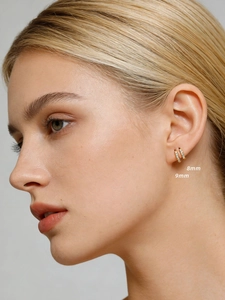 Detail view comparing 8mm and 9mm gold huggie earrings with cubic zirconia on ear
