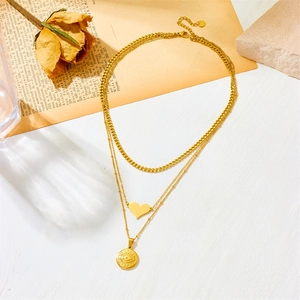 Detail of layered gold stainless steel necklace with heart and eye pendants on vintage books