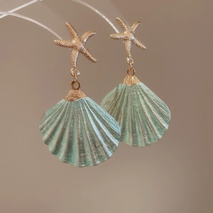 Detailed shot of starfish and mint green shell earrings with polished gold finish