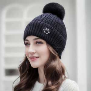 Close-up of thick knit beanie with fluffy pompom and smiley patch on the front