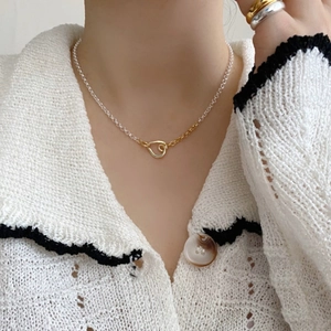 Close-up of minimalist bicolor heart pendant necklace on collarbone for women