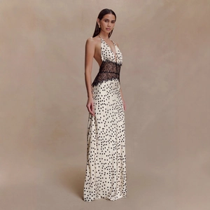 Detail of elegant white polka dot halter maxi dress with black lace waist stitching