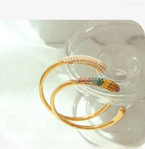 Détail de bracelets plaqués or 18k avec perles blanches et strass colorés brillants