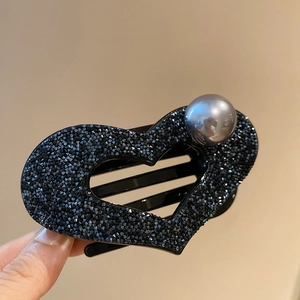 Detailed macro view of heart-shaped hair claw with black crystals and grey pearl accent