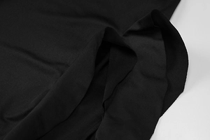Detailed macro view of black dress fabric texture with asymmetric layered cut and slit