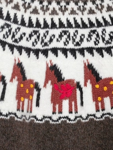 Detailed close-up of ethnic jacquard knit pattern featuring red horse motifs on brown wool